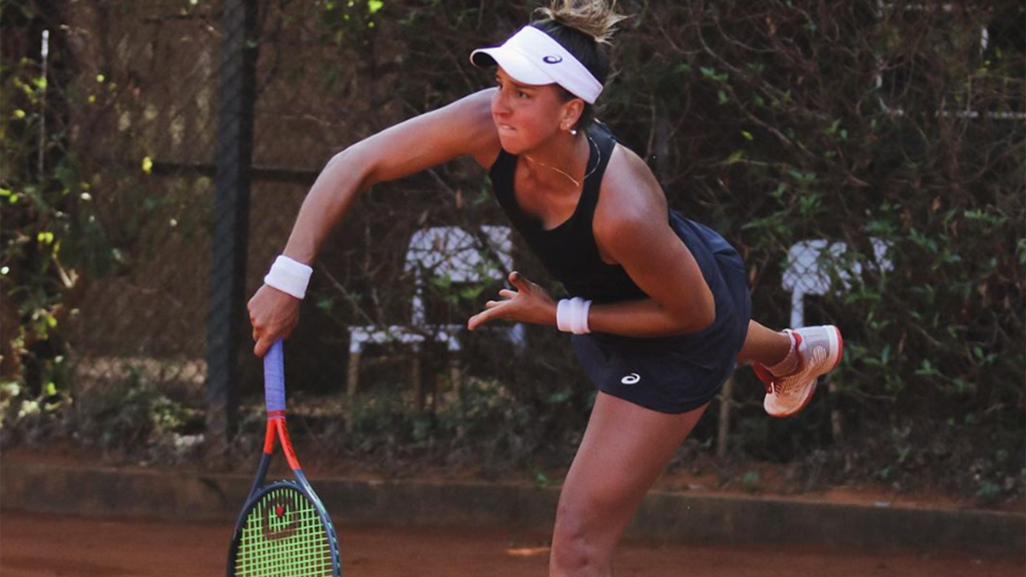 Ingrid Martins lands a perfect serve during a clay court match.